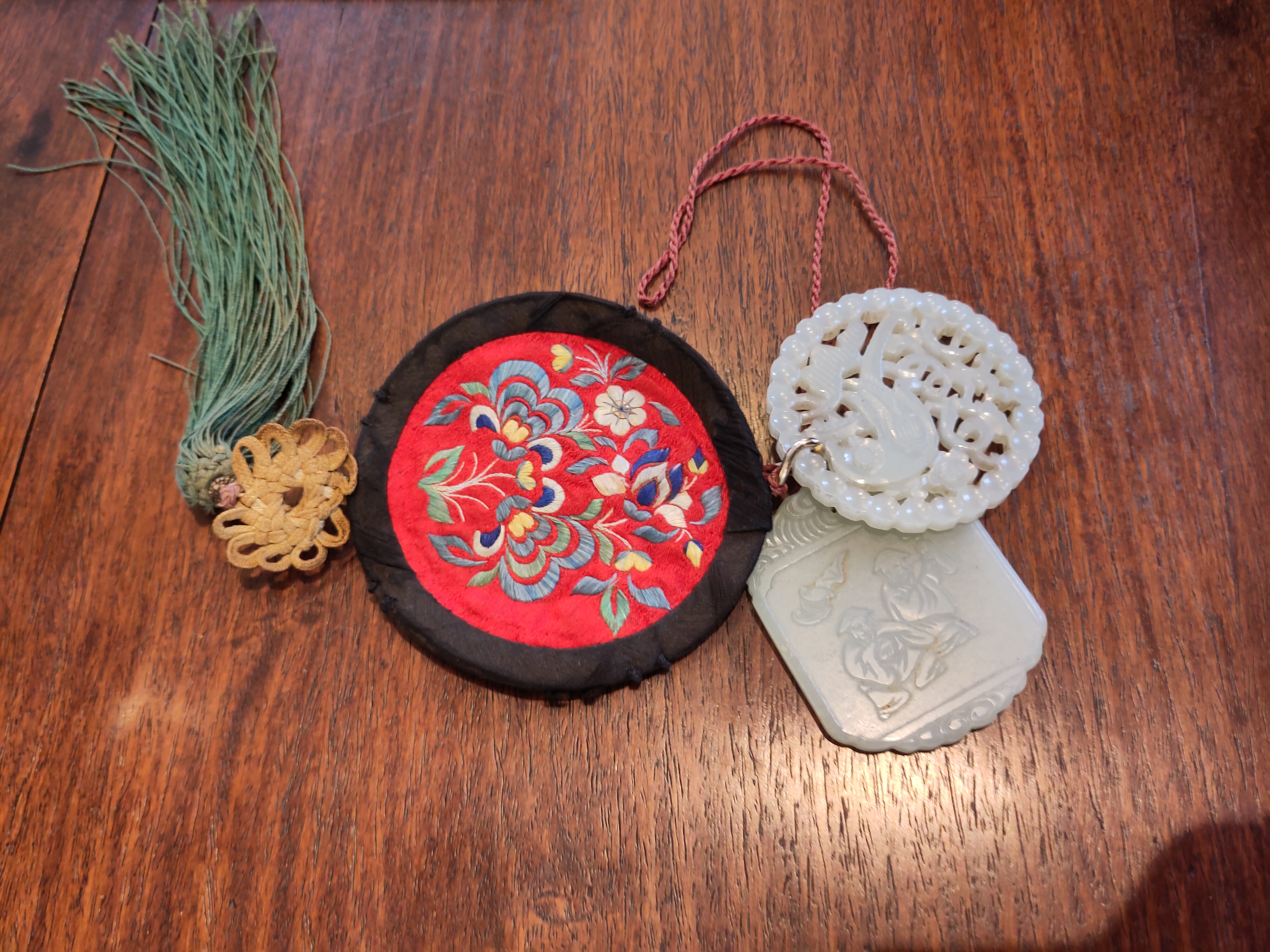 Deux amulettes en jade (néphrite) sculpté chinois du XIXe siècle, reliées à une bourse en soie brodée, diamètre 5,5 cm et hauteur 6 cm