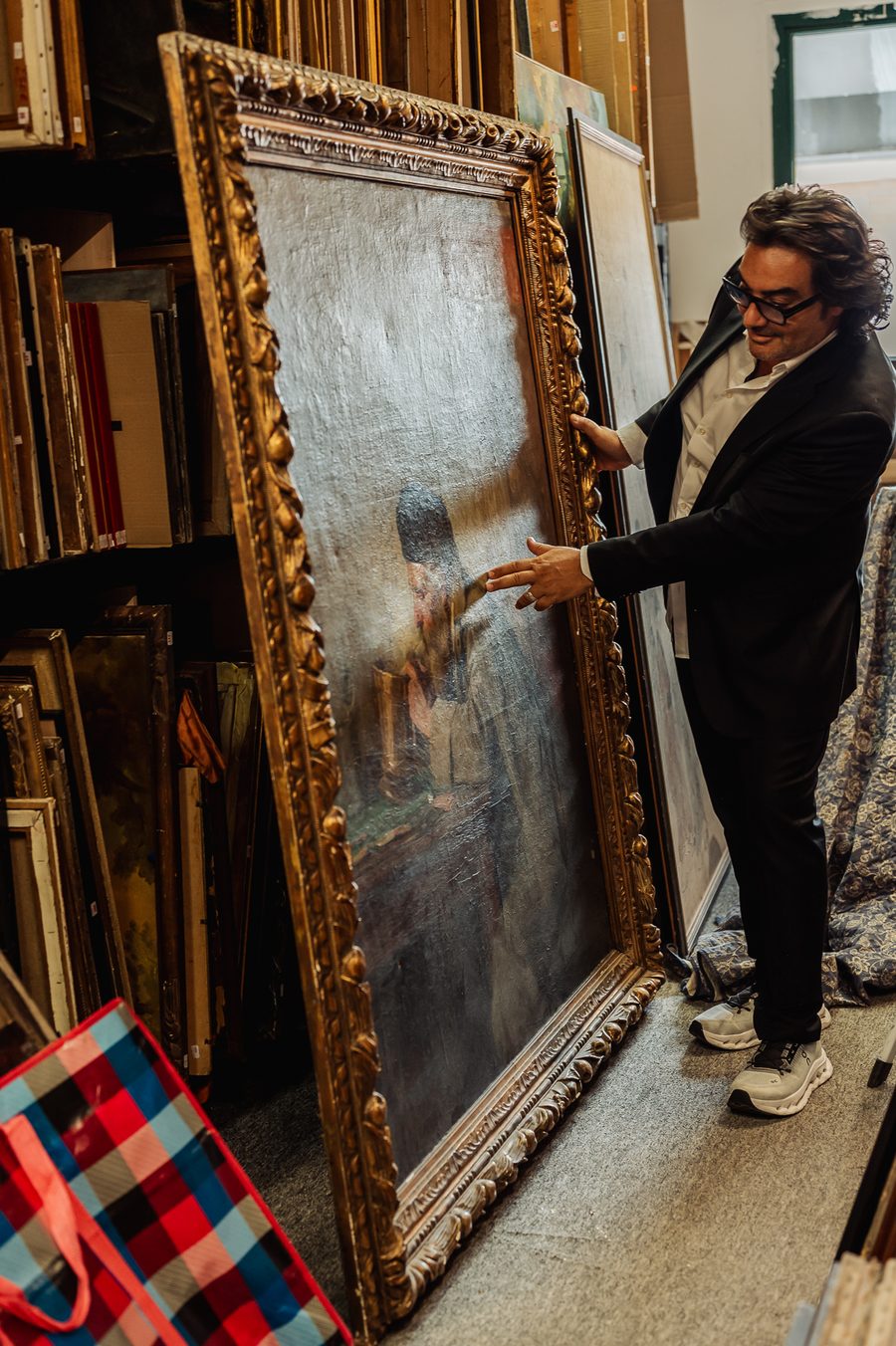 Éric Benhamou désigne le personnage d'une grande toile claire montée dans un cadre baroque doré, dans la réserve des tableaux.